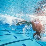 Underwater photo of a woman swimmer performing a flip turn in a swimming pool.
