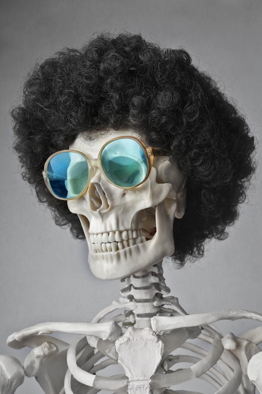 A skeleton wearing an afro wig and sunglasses, set against a gray background.