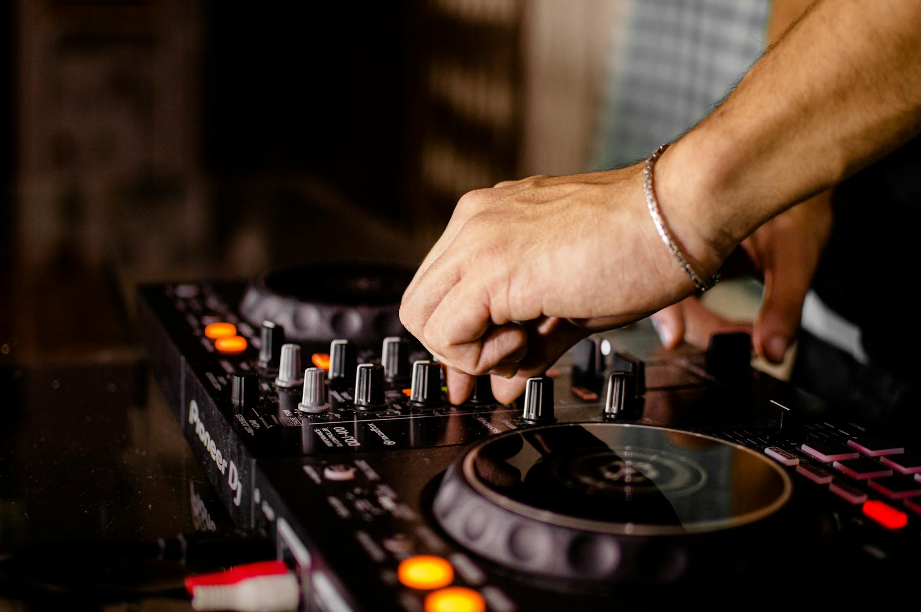 DJ adjusting the knobs on a professional mixing board in a close-up shot, focusing on equipment details.