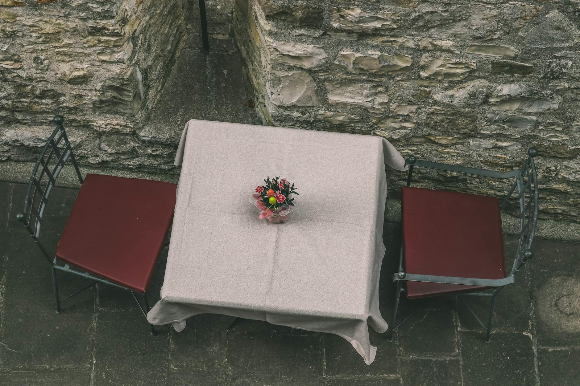 Charming outdoor patio table with floral centerpiece, ideal for intimate dining.