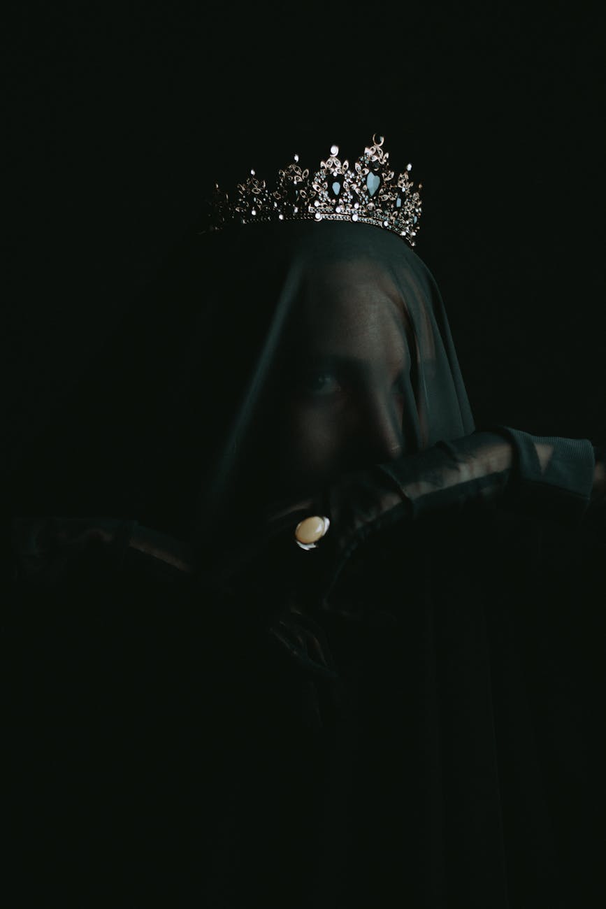 Ethereal portrait of a woman in darkness wearing a jeweled crown and veil.