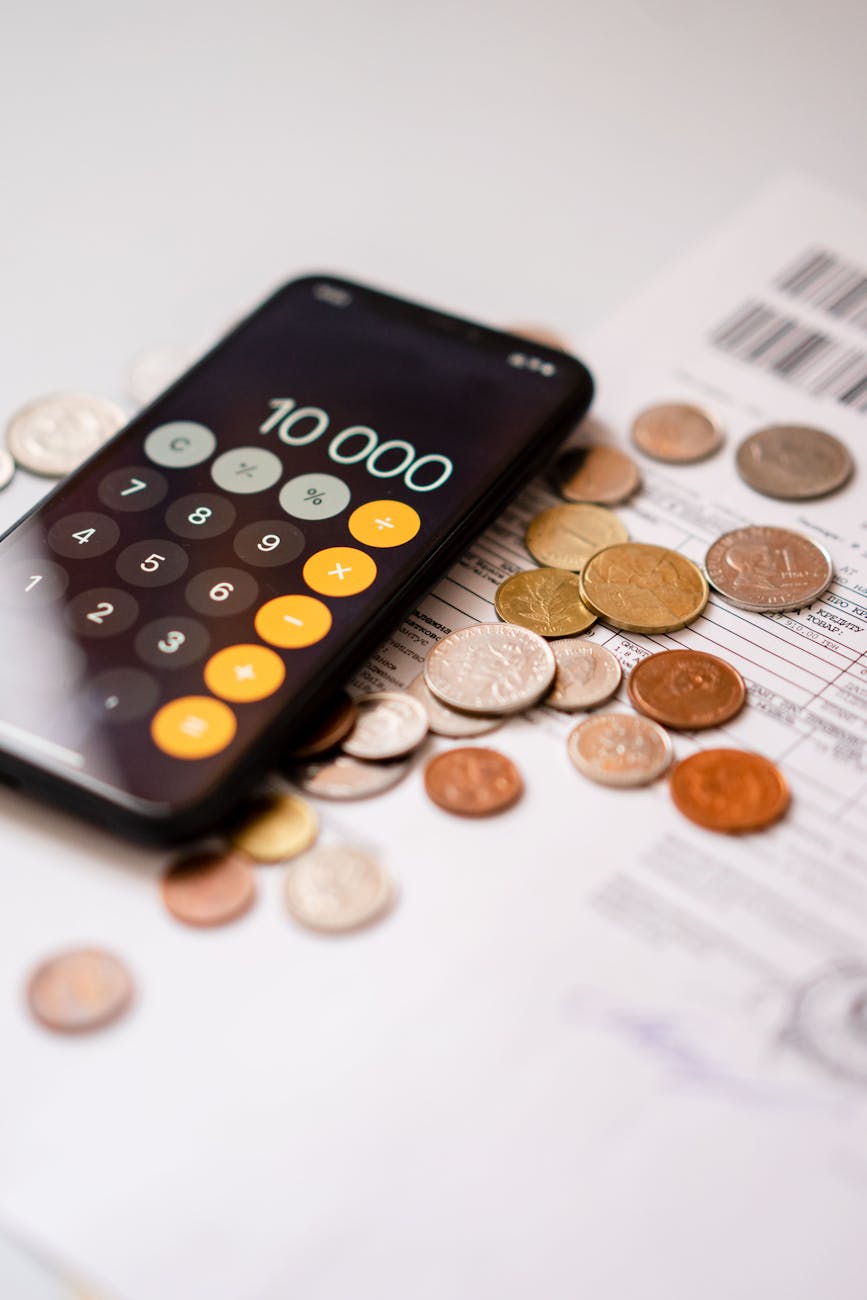 Smartphone calculator app displaying 10000 amidst scattered coins and documents.