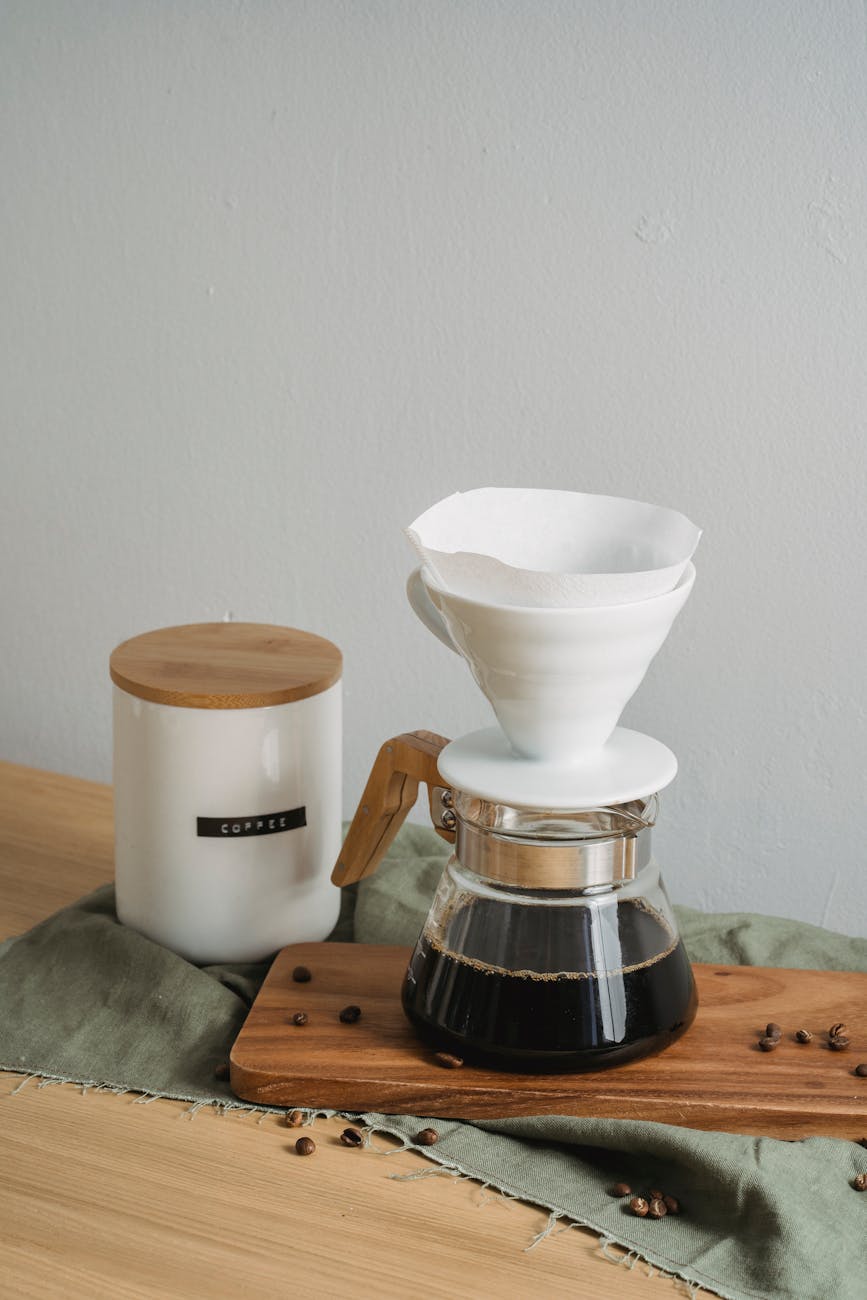 Aesthetic coffee brewing setup with ceramic and glass pieces on wooden board.