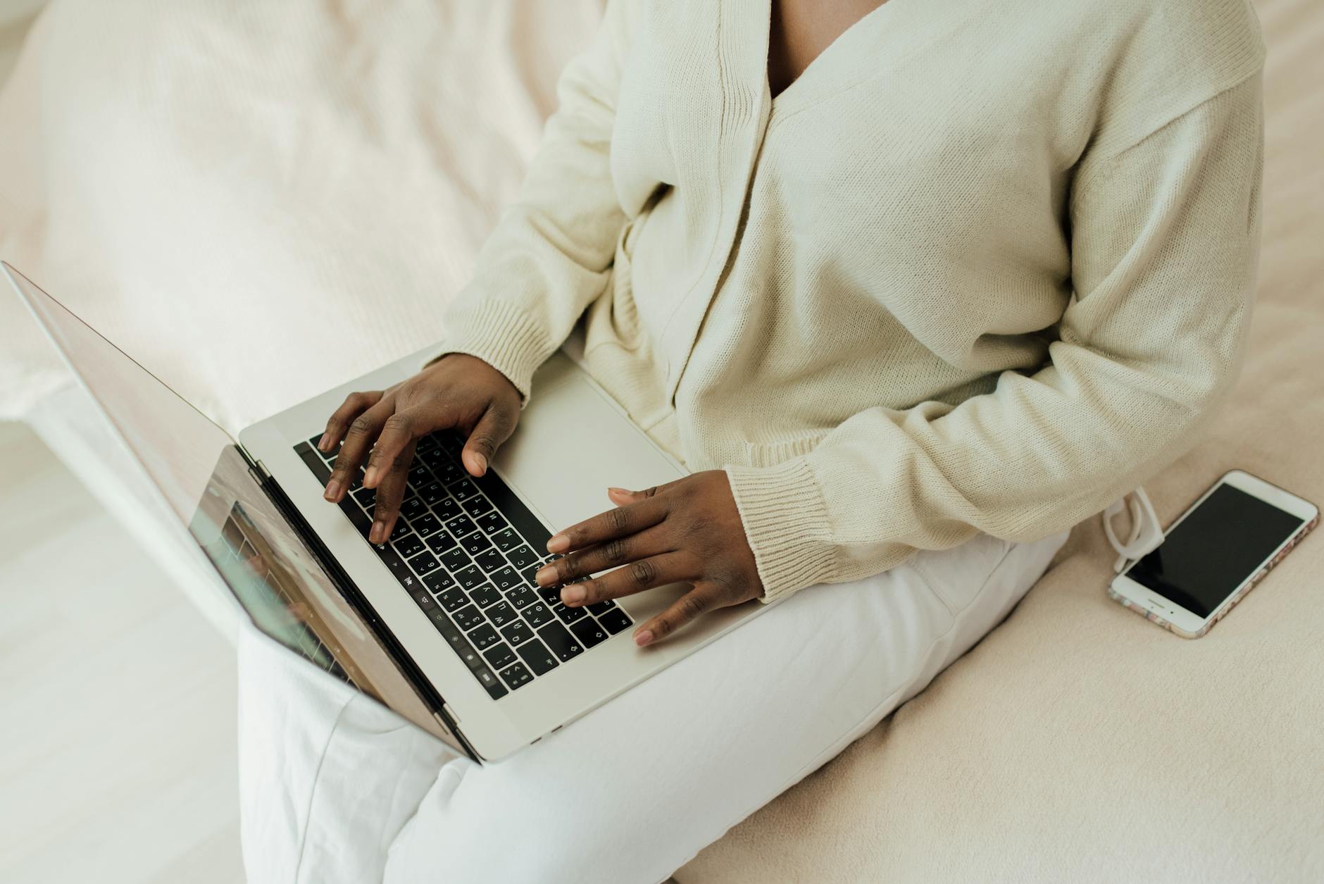 Person working remotely on laptop with smartphone nearby. Cozy home setting, lifestyle focus.