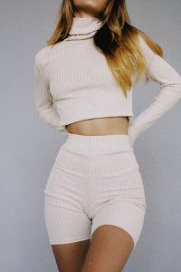 Stylish young woman wearing a ribbed crop top and shorts in a neutral tone.