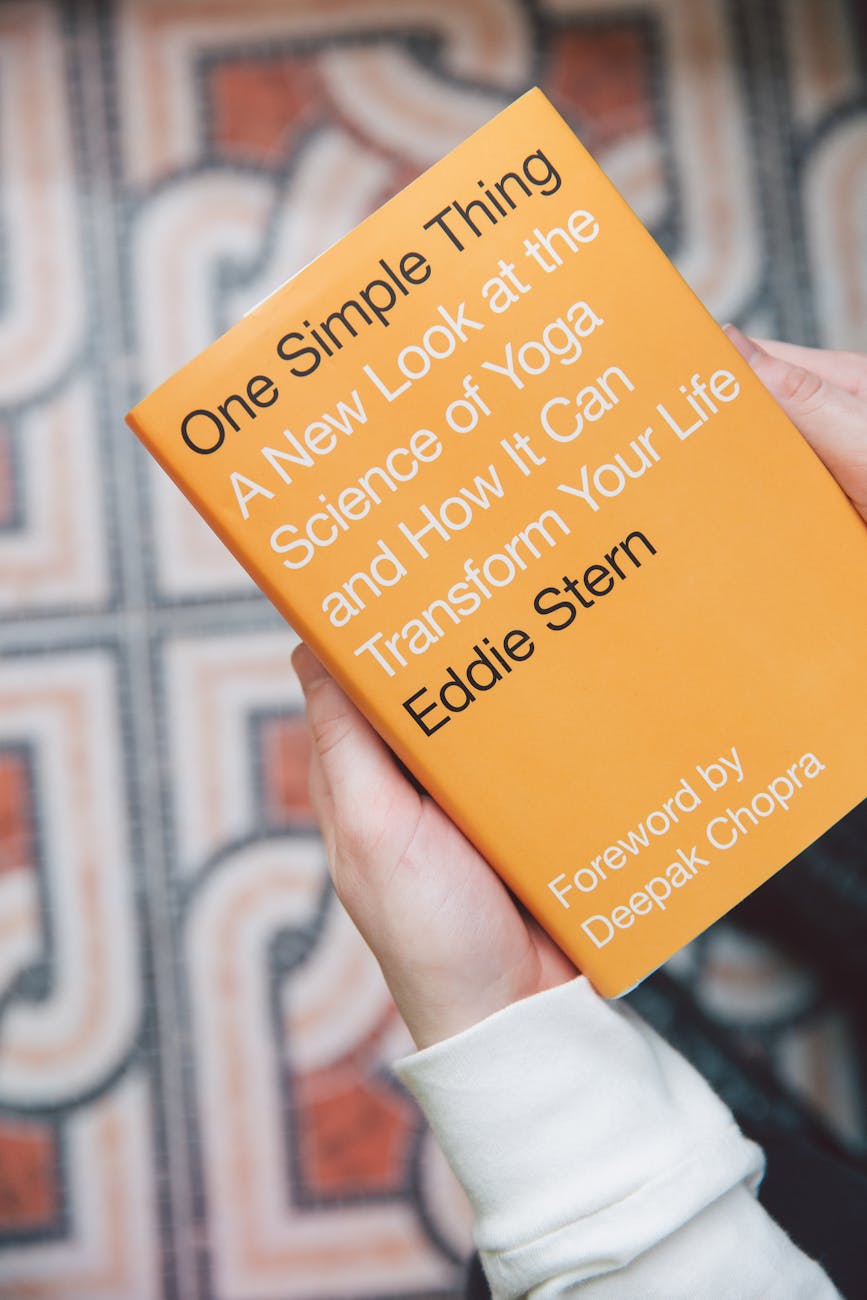 Close-up of hands holding Eddie Stern's book on yoga science, indoors.